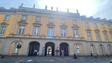Historic building with large arched entrance, sunny day.