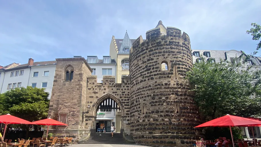 Historic stone tower with modern buildings nearby.