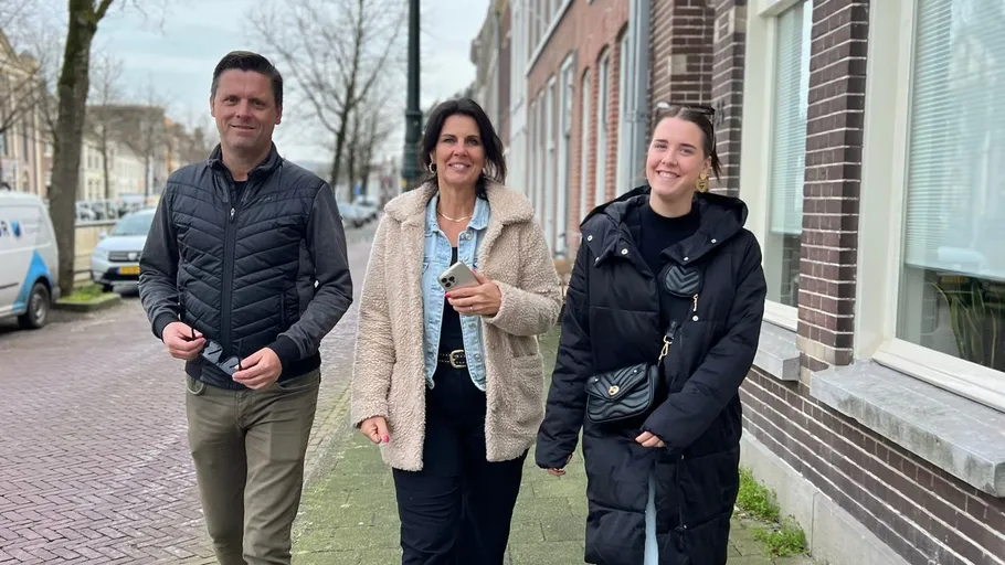 Three people walking on a city sidewalk.