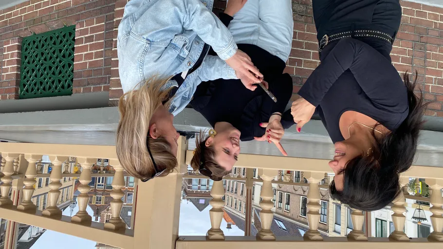 Drei Personen unterhalten sich draußen, Stadt im Hintergrund.