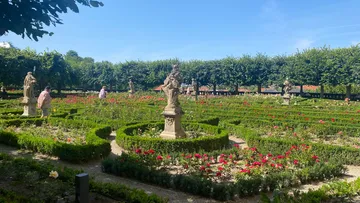 Sculptures in manicured garden with visitors present.