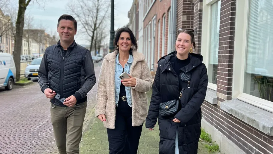 Three people walking on a sidewalk.