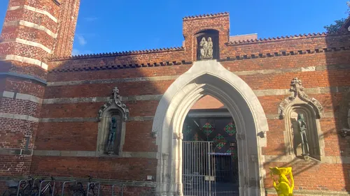 Gothic archway with brick wall, shadowed person.