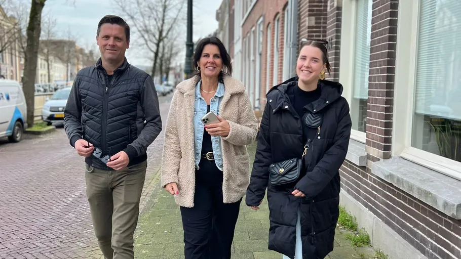 Three people walking on a city sidewalk.