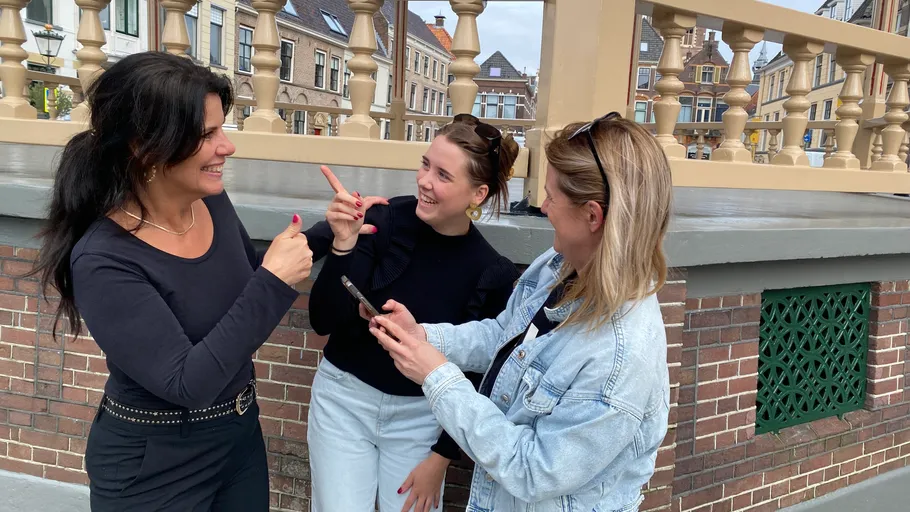 Drei Frauen sprechen, halten Handy, städtische Umgebung.