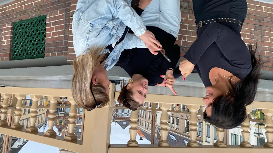 Drei Frauen sprechen, halten Handy, städtische Umgebung.