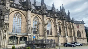 Gothic cathedral exterior with sculptures, overcast sky.