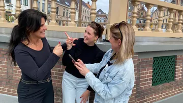 Three women chatting on a balcony.