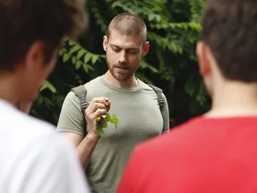 Man shows plant leaf to a group of listeners.
