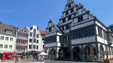 Historisches Gebäude mit Zierfassade, sonniger Tag.