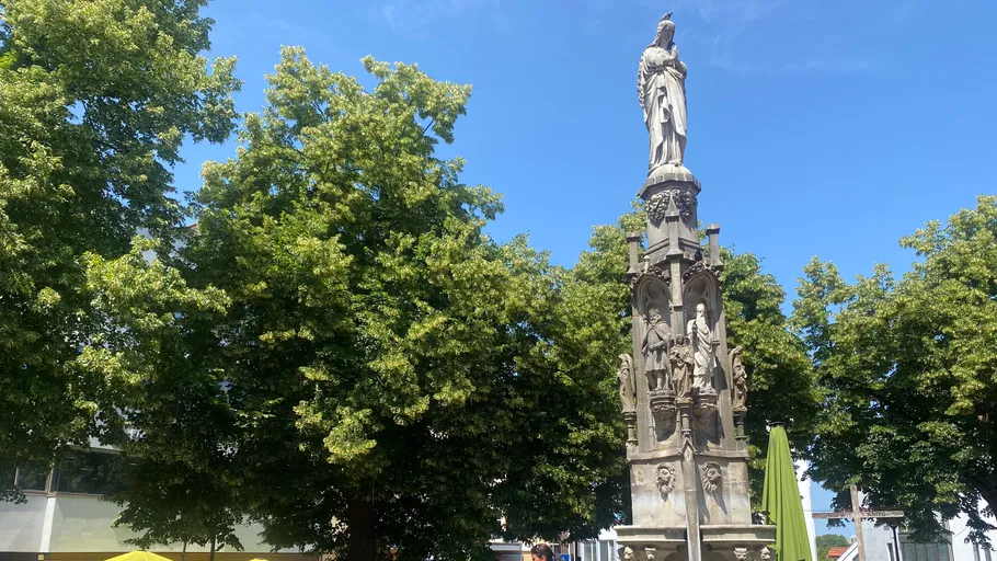 Steinstatue von grünen Bäumen umgeben.