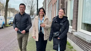 Three people walking on suburban street.