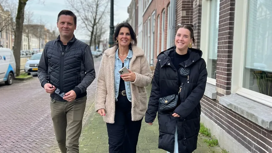 Three people walking on suburban street.
