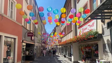 Bunte Laternen hängen über einer Straße.