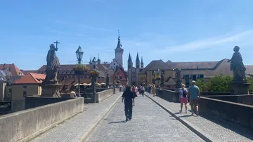 People walking across historic stone bridge.
