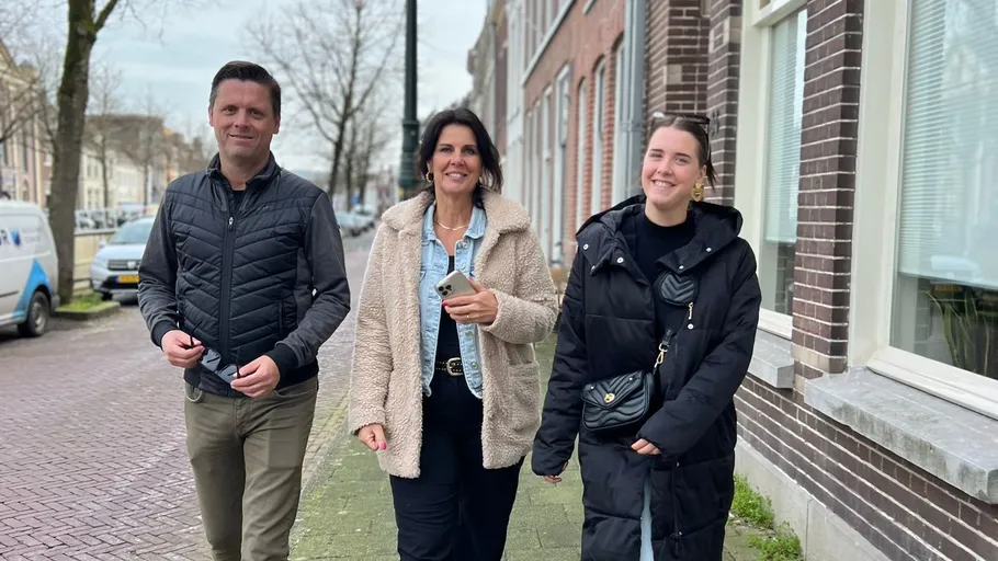 Three people walking on urban sidewalk.