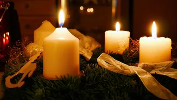 Kerzen brennen auf einem Adventskranz.