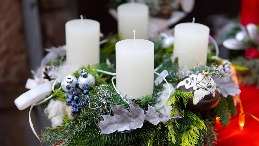 Advent wreath with four white candles, outdoor setting.