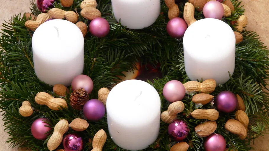 Weihnachtskranz mit Kerzen auf Tisch.