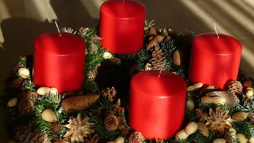 Red candles on decorative Christmas wreath.