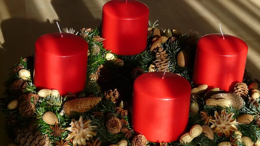 Rote Kerzen auf dekorativem Weihnachtskranz.