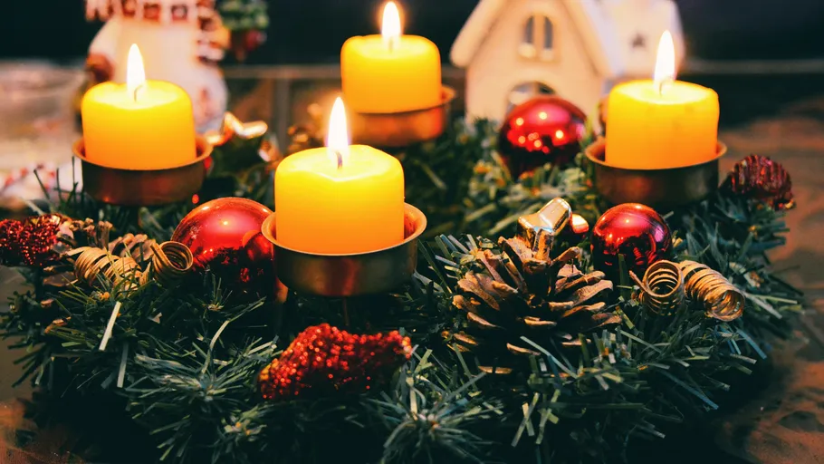 Kerzen brennen auf geschmücktem Adventskranz.