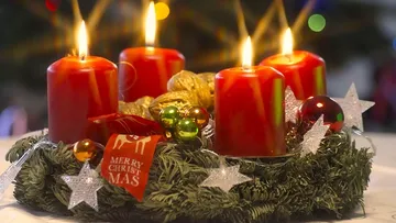 Red candles lit on a Christmas wreath.