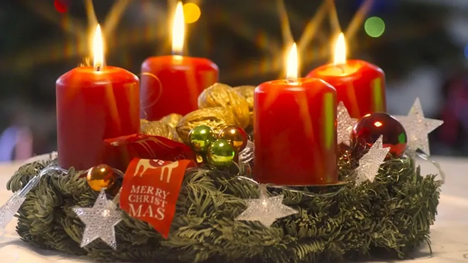 Red candles lit on a Christmas wreath.