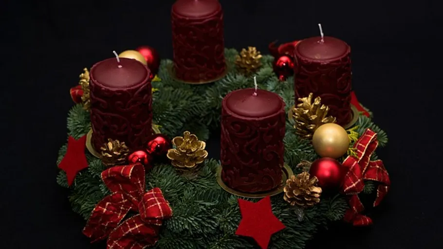 Red candles on decorated evergreen wreath.