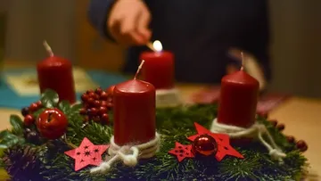 Hand lighting candle on festive wreath.