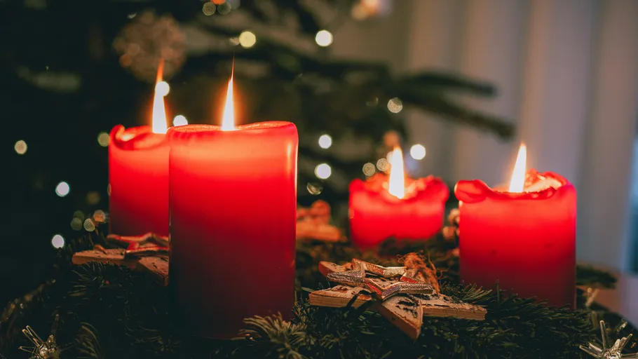 Rote Kerzen brennen auf einem Adventskranz.