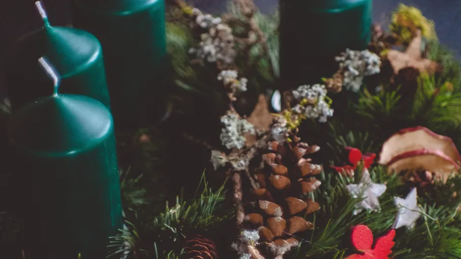 Green candles on decorative Christmas wreath.