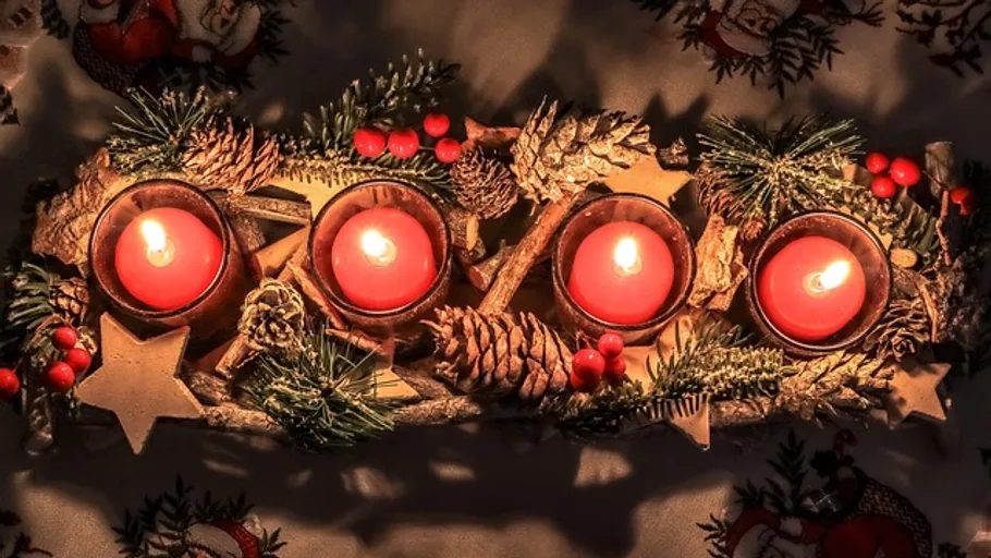Four red candles lit on festive arrangement.