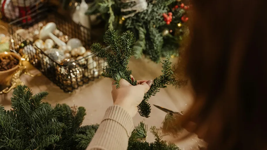 Person fertigt drinnen einen Weihnachtskranz an.