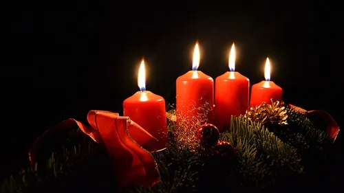 Four lit red candles on a wreath.