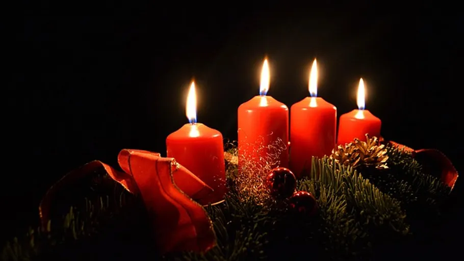 Four lit red candles on a wreath.