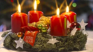 Rote Kerzen brennen auf Adventskranz Tisch.