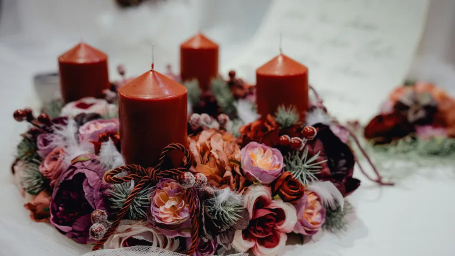 Red candles with floral wreath on table.
