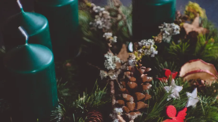 Grüne Kerzen auf dekorativem Adventskranz.