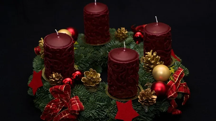 Adventskranz mit roten Kerzen und Dekorationen.