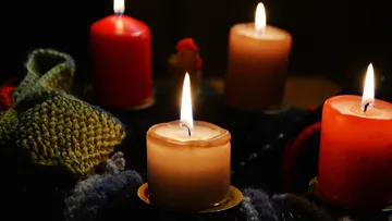 Candles lit in dark room with knitted cloth.