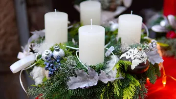Vier Kerzen auf einem geschmückten Adventskranz.