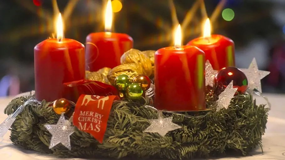 Vier brennende rote Kerzen auf Adventskranz.