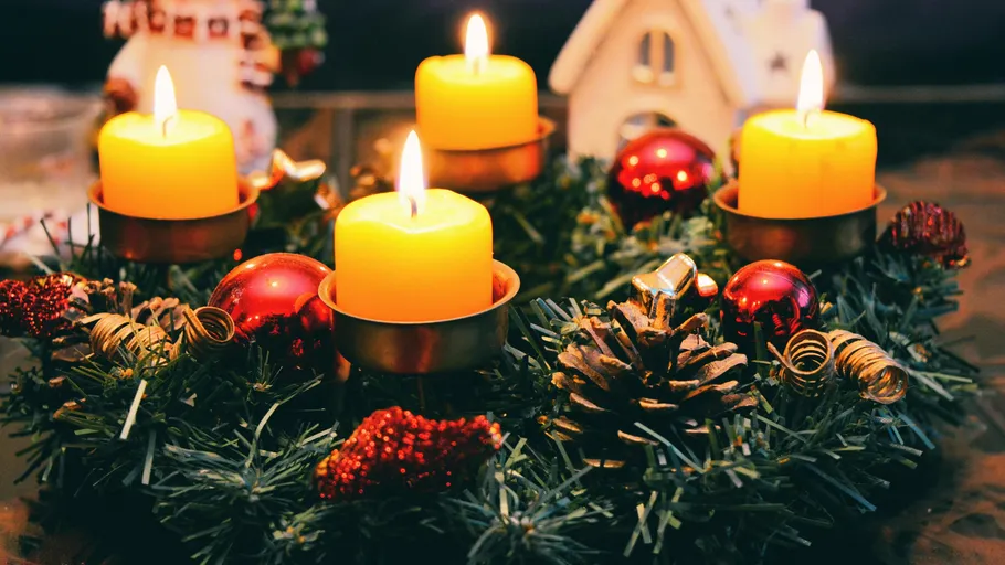 Vier brennende Kerzen auf einem Weihnachtskranz.