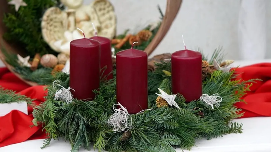 Rote Kerzen auf festlichem Grünkranz.
