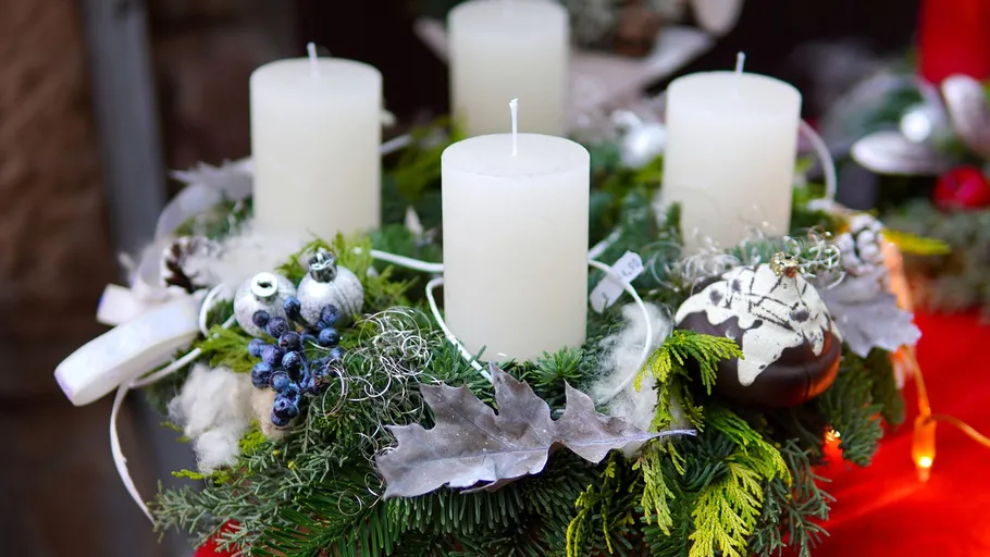 Festlicher Kranz mit vier Kerzen und Ornamenten.