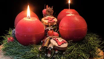Rote Kerzen auf einem Adventskranz mit Dekorationen.