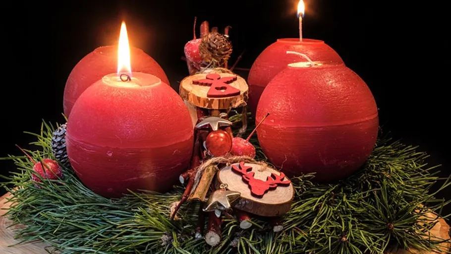 Rote Kerzen auf einem Adventskranz mit Dekorationen.