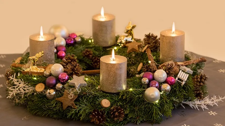 Adventskranz mit brennenden Kerzen und Dekorationen.
