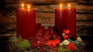 Four lit red candles on a wreath.